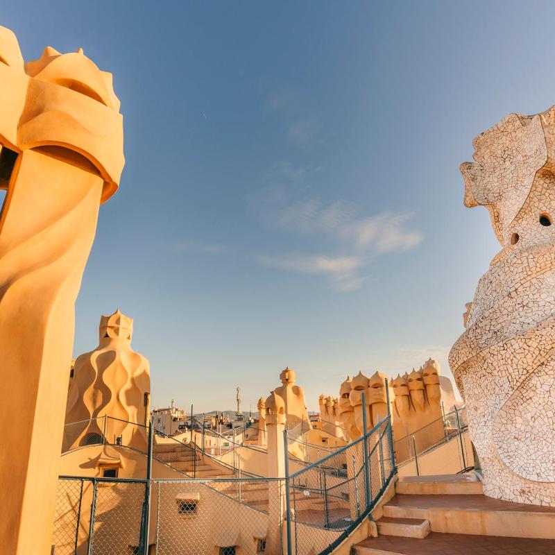 Azotea de Casa Milà durante la hora dorada, con las chimeneas recortadas contra el cielo del atardecer
